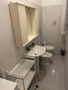 La salle de bains blanche est pourvue d'un lavabo et de toilettes. dans l'établissement Ale E-Commerce Holiday Home, à Buccinasco