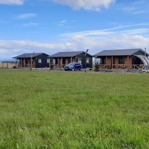 a row of houses with a car parked in a field at Cabañas Natales Rotundo in Puerto Natales