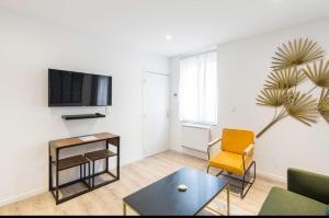 a living room with a couch and a table and a tv at Désirée Logement Cosy et Charmant 1 er étage in Reims