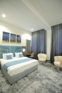 una habitación de hotel con una cama grande y sillas en MaxWell Hotel & SPA, en Tashkent