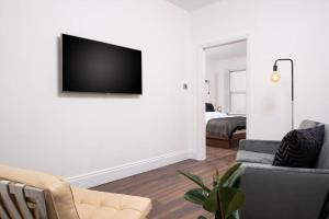 a living room with a couch and a tv on a wall at Super King , Stunning apartment in Harrogate. in Harrogate