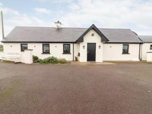 a white house with a black roof and a driveway at Laharn Cottage in Killorglin