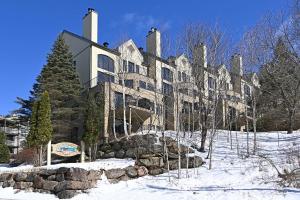 a large building in the snow with a tree at Tremblant Rocher Soleil Ski In Ski Out 2 Bedroom in Mont-Tremblant