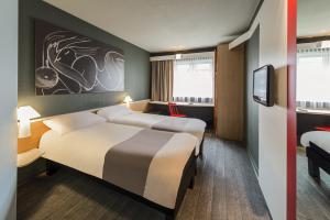 a hotel room with two beds and a tv at ibis München Parkstadt Schwabing in Munich +60 photos