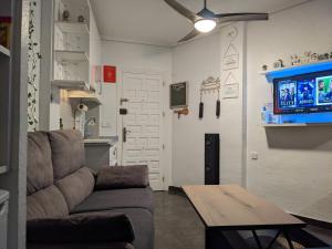 uma sala de estar com um sofá, uma mesa e uma televisão em Estudio con Piscina, Playa y Wifi em Denia