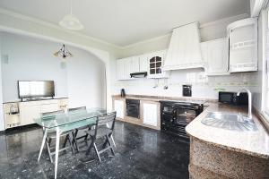 cocina con armarios blancos y mesa de cristal en Apartamento da Pedra e da Auga en Meis