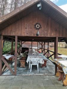 einem großen Holzpavillon mit einem Tisch und Bänken in der Unterkunft Fontana erdélyi vendégház in Odorheiu Secuiesc