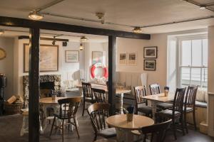 a restaurant with tables and chairs and a fireplace at The Old Success Inn in Sennen Cove