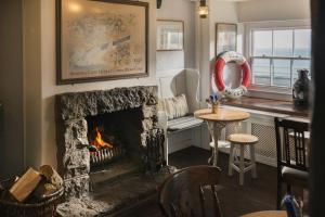 a living room with a fireplace and a table at The Old Success Inn in Sennen Cove