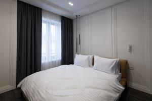 1 dormitorio con 1 cama con sábanas blancas y ventana en Cristal Garden Chalet en Bukovel