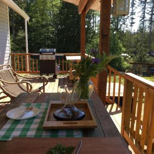a wooden table with a vase of flowers on a deck at Cozy ,artistic cottage in a garden setting close to the beach and hiking trails. in Powell River