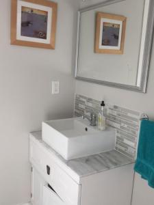 a white bathroom with a sink and a mirror at Cozy ,artistic cottage in a garden setting close to the beach and hiking trails. in Powell River