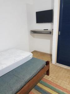 1 dormitorio con 1 cama y TV de pantalla plana en Apartamento perto de praia Dos Anjos 2 en Arraial do Cabo