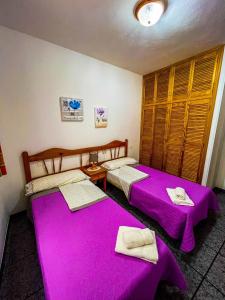 2 łóżka w pokoju z fioletową pościelą w obiekcie Los Camarones w mieście La Restinga