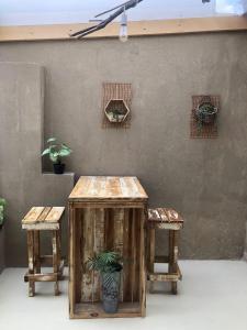 einen Holztisch und zwei Hocker mit einer Pflanze in der Unterkunft LaCasita SP in San Pedro