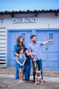 a family posing in front of a blue building with a dog at Hotel Casa Pino, Tu Casa en Ataco in Concepción de Ataco
