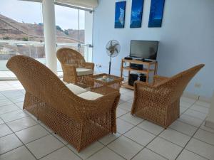 un soggiorno con sedie in vimini e TV di Departamento super cómodo Playa Naplo a Naplo