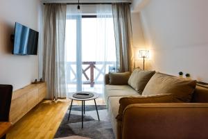 a living room with a couch and a large window at Nivalis Residence *apartman 20* in Jahorina