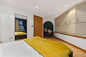 Un dormitorio con una cama con una manta amarilla. en Spacious 2 Bed Urban Jungle Flat, Central London, en Londres