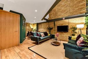 a living room with couches and a brick wall at Spacious 2 Bed Urban Jungle Flat, Central London in London