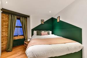 a bedroom with a large bed with a green headboard at Spacious 2 Bed Urban Jungle Flat, Central London in London