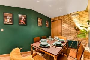 a dining room with a wooden table and green wall at Spacious 2 Bed Urban Jungle Flat, Central London in London