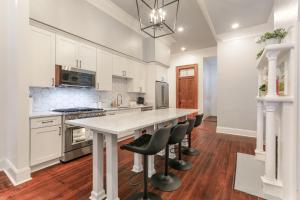 a kitchen with white cabinets and a large island with bar stools at Canal Street Mini Mansion Sleeps 15 in New Orleans