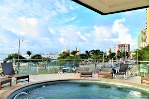 Una piscina con sillas y vista a una ciudad. en Particular Iracema Residence, en Fortaleza