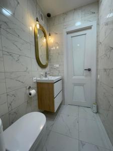 een badkamer met een toilet, een wastafel en een spiegel bij Isy-Baizakova 133 Str by StayInn in Pavlodar +12 foto's