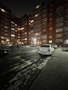 ein weißes Auto, das nachts auf einem Parkplatz parkt in der Unterkunft Люкс Исы-Байзакова 133 by Slissenko Inn, Новый дом in Pawlodar