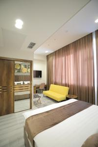 Habitación de hotel con cama y silla amarilla en MaxWell Hotel & SPA, en Tashkent