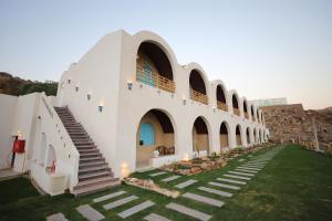 a large white building with stairs and a grass yard at Noprea Boutique Hotel in Aswan