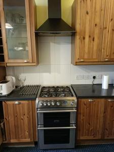 eine Küche mit einem Herd und Holzschränken in der Unterkunft City centre Flat - sleep upto 4 in Edinburgh