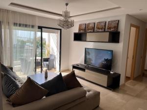 uma sala de estar com um sofá e uma televisão de ecrã plano em Superbe appartement avec piscine em Rabat