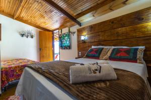 a large bed in a room with wooden walls at Pousada Casa do Geninho in Conceição da Ibitipoca