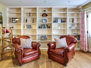 two leather chairs in a room with a book shelf at Rose Cottage in North Elmham