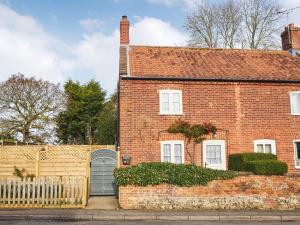 a brick house with a gate and a fence at Rose Cottage in North Elmham
