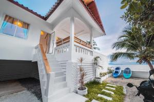 a white house with the ocean in the background at Sunset Lover Beach Residence in Thong Sala