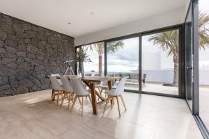 a dining room with a wooden table and white chairs at Villa Serenity in Tías