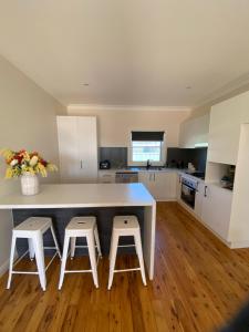 a kitchen with a white counter and two stools at Secret at Sussex Inlet Units in Sussex inlet