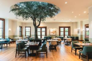 un restaurante con mesas, sillas y un árbol en Hotel Viata en Austin