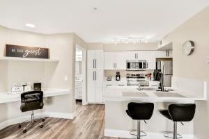 a kitchen with white cabinets and black chairs at Villa del Sol #324 in Kissimmee