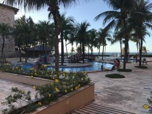 un complejo con piscina y palmeras en Kariri Beach - Suíte Standard, en Cumbuco