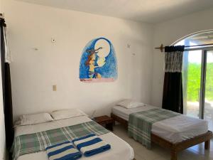 Habitación con 2 camas y una pintura en la pared. en Casa Kayab en Puerto Morelos