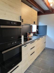 a kitchen with wooden cabinets and black appliances at Maison cosy proche de font romeu in Latour-de-Carol