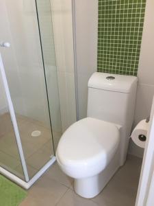 a bathroom with a toilet and a glass shower at Flat Capitania Varam in Guarujá