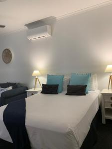 a bedroom with a large white bed with blue pillows at The Mediterranean Port Douglas in Port Douglas