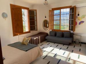 a bedroom with a bed and a couch and windows at Caminito del Rey Piscina Campo fútbol 20 adultos in Alora