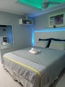 1 dormitorio azul con 1 cama con 2 toallas en ** SUITE PRIVATIVA PRAIA DO FORTE CABO FRIO **, en Cabo Frío