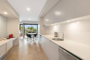 a white kitchen with a sink and a table at Peppers Plunge Pool Perfection 2br spa suite in Kingscliff
